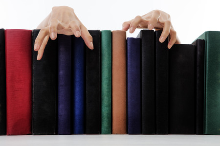 creepy hands coming over books on a bookshelfの写真素材