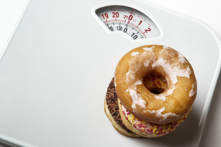 stack of different flavor donuts shot on scale for weighing yourselfの写真素材
