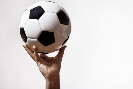 male hand holding up a traditional black and white footballの写真素材