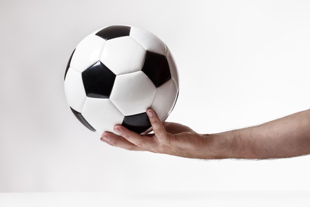 male hand holding a traditional black and white footballの写真素材