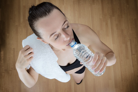 fitness woman drinking water after a workout, view point is high above the modelの写真素材