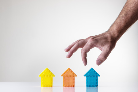 kids building blocks made into a shape of a house with a mans hand picking what house he wantsの写真素材