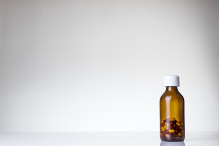 pill bottle with a few pills in the bottle shot in the studio on white perspex backgroundの写真素材