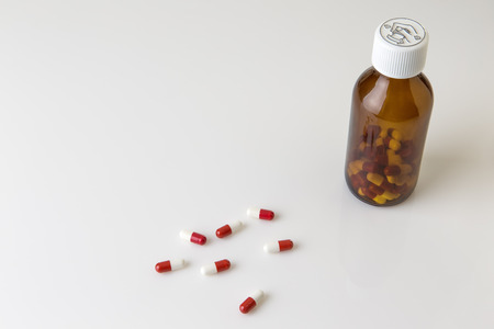 pills and pill bottle shot in the studio on white perspex backgroundの写真素材