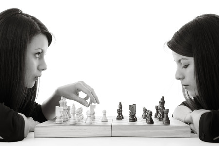 young woman playing chess against herself shot in the studioの写真素材