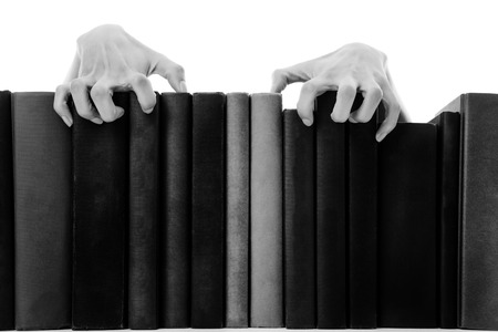 creepy hands coming over books on a bookshelfの写真素材