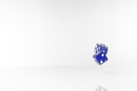 black and white image with blue tint of  two dice rolling along on white background with blur and movementの写真素材