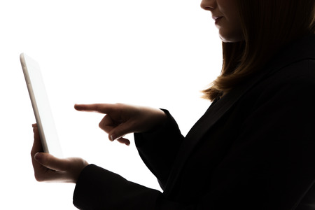 silhouette of a businesswoman using a tablet, about to touch the screen with her out straight pointed fingerの写真素材
