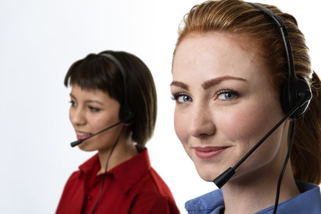 Two business woman wearing headset working hard to make you happyの写真素材