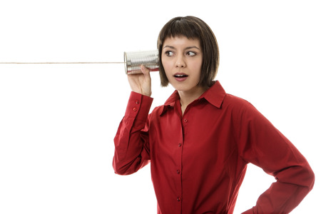 business woman  using tin cans to listen to someone on the other end of the lineの写真素材