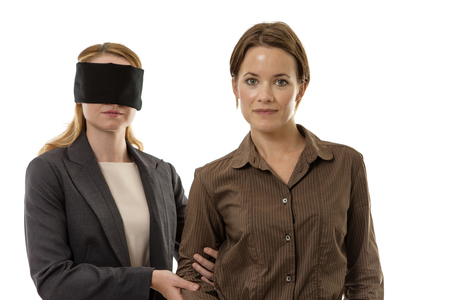 two business woman one blindfolded and the other helpingの写真素材