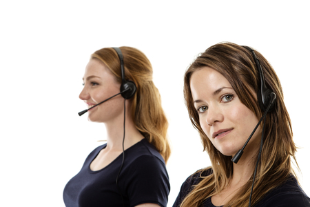 two woman one standing in front in focus wearing a headset talkingの写真素材