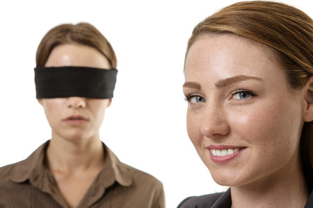 two business woman one blindfolded and the other helpingの写真素材