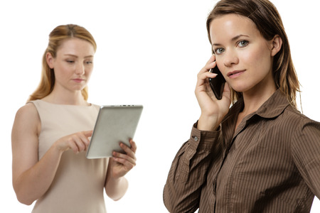 two business women one in front of the other talking on a mobile phoneの写真素材