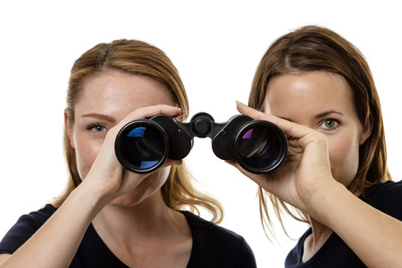 Two business woman looking through the same pair of binocularsの写真素材