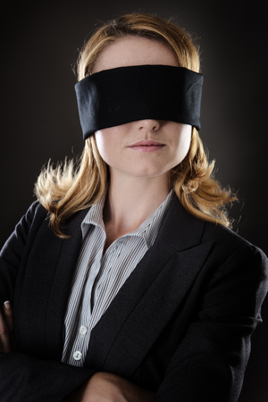 portrait of a business woman blind folded shot in the studio on gray backgroundの写真素材