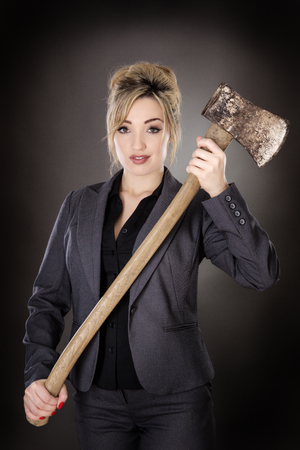 business woman holding a large axe shot in the studio on a gray backgroundの写真素材