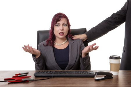 secretary sitting at desk with a mans hand on her shoulder  feeling uncomfortableの写真素材