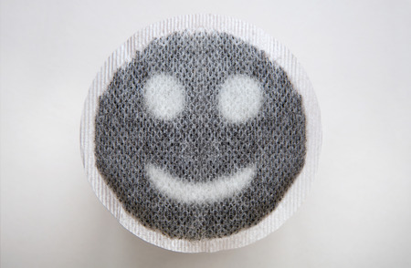 round tea bag with tea leaves in the shape of a happy face on itの写真素材