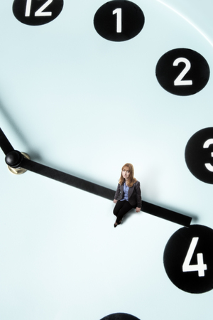 business woman sitting on a clockの写真素材