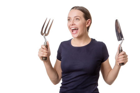 happy woman ready to do some gardening holding a trowel and fork shot in the studioの写真素材