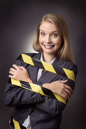 Business model is tied up with a black and yellow stripe tape wound around her. shot on a grey background.の写真素材