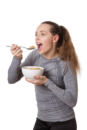 happy woman wearing fitness clothes eating cerealの写真素材