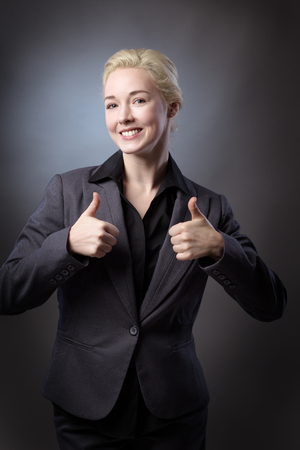 Studio shot of a business model making the thumbs up gesture, shot on a grey backgroundの写真素材