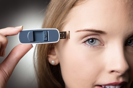 Close-up head shot of a business woman holding a memory stick to the side of her headの写真素材