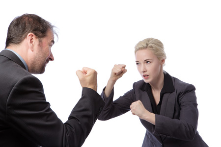 Studio shot of two co-workers wearing suits, fightning in the office, isolated on a white background.の写真素材