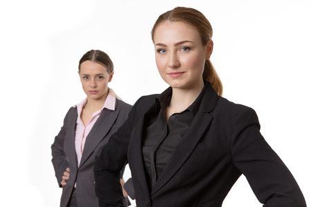 Upper body studio shot of two happy, pretty business models wearing suits, looking serious and professional.  isolated on whiteの写真素材