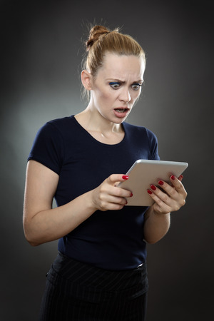 business model with a tablet computer with a concerned expression on her face.  shot on a grey backgroundの写真素材