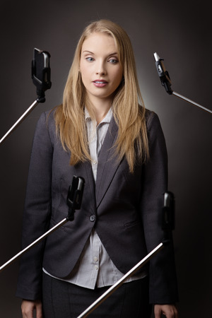 business woman getting annoyed with the number of selfie stick around herの写真素材