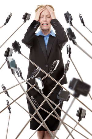 business woman surrounded by selfie stick not looking very happyの写真素材