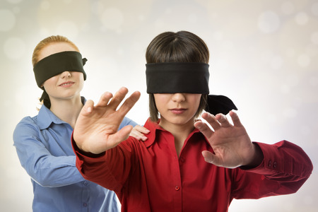 two business woman blind folded leading the otherの写真素材