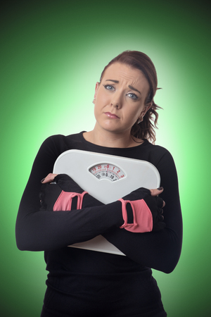 unhappy looking woman holding scales の写真素材