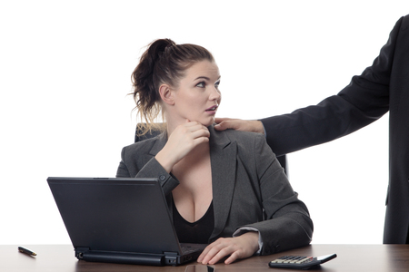 business woman sitting at her desk being sexual harassment unsure what to doの写真素材