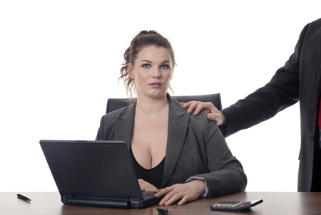 business woman sitting at her desk being sexual harassment unsure what to doの写真素材