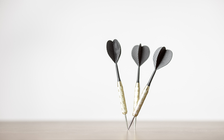 three playing darts in wooden table top
