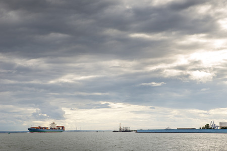 seascape taken from canvey island looking out at the estuary with a container ship going out to sea loaded up with goodsの写真素材