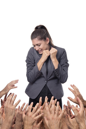 business woman being pulled down by hands all around herの写真素材