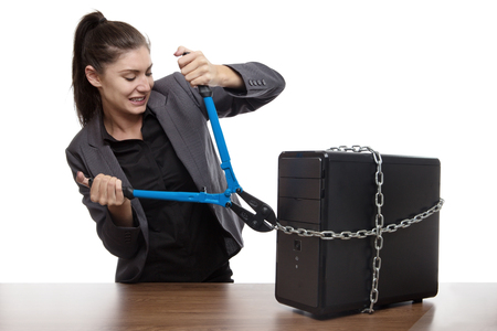 Computer locked up and business woman with holding bolt cutters trying to work out how to set it freeの写真素材