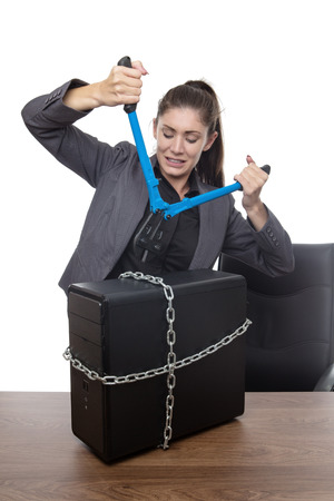 Computer locked up and business woman with bolt cutters trying to set it freeの写真素材
