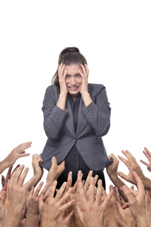 business woman being pulled down by hands all around herの写真素材