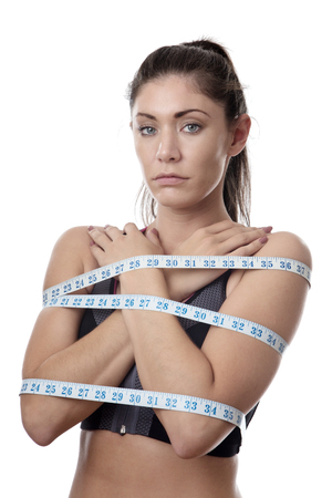 unhappy looking model with tape measures wrapped around her bodyの写真素材