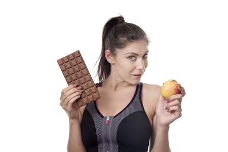 fitness woman holding a chocolate bar and appleの写真素材