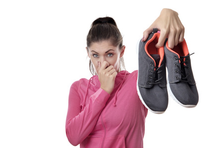 fitness woman holding up her smelly exercise shoesの写真素材