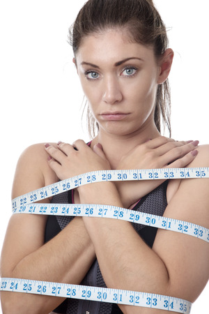 unhappy looking model with tape measures wrapped around her bodyの写真素材