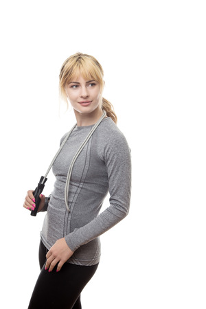 standing fitness woman in a grey top with a skipping rope around her neckの写真素材