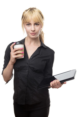 standing blonde haired business woman holding a coffee cup and a computerの写真素材
